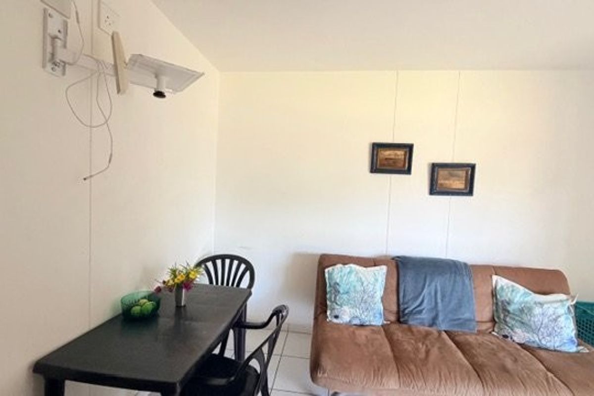 A compact living area featuring tiled flooring and a wall-mounted television bracket, requiring cosmetic updates to improve the overall finish.