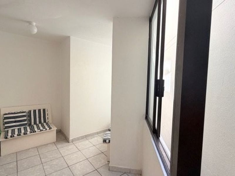 A compact balcony or enclosed patio area featuring tiled flooring and a large sliding window, providing a functional outdoor transition space.