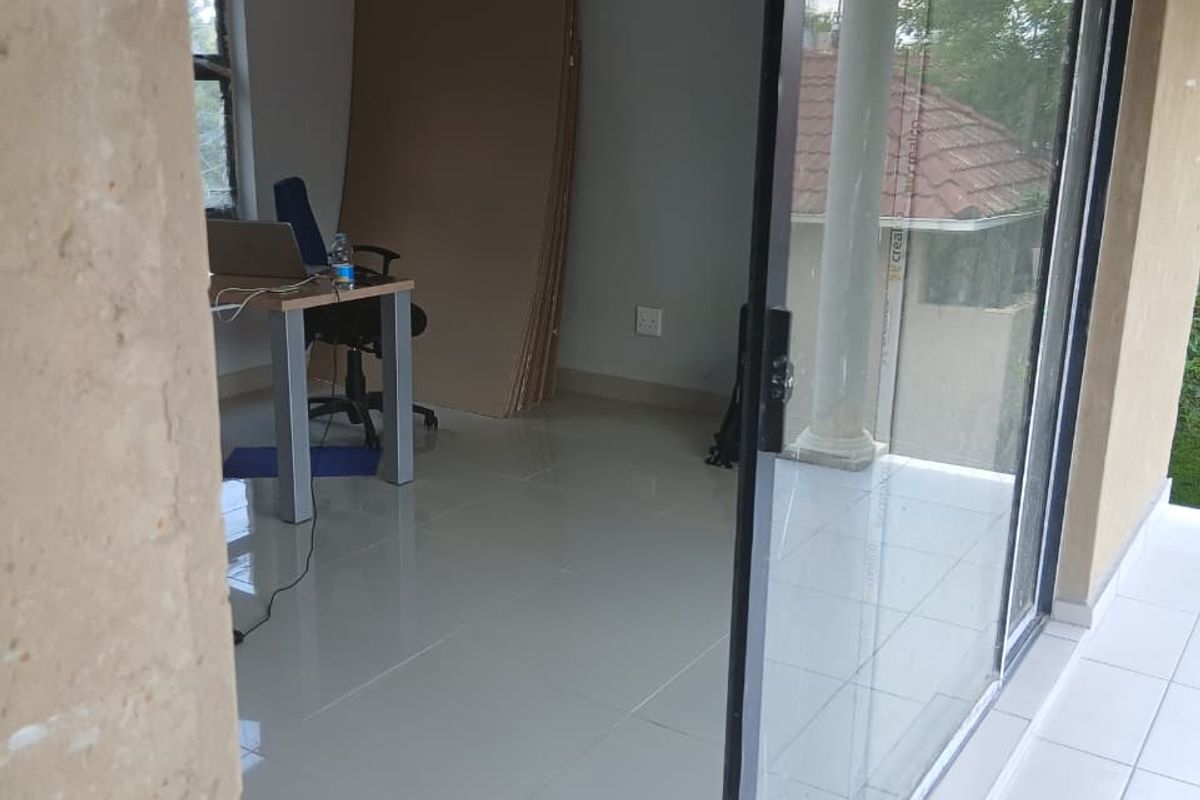 A bright, empty office space featuring large sliding glass doors that provide access to an outdoor patio area.