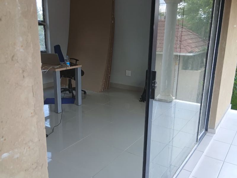 A bright, empty office space featuring large sliding glass doors that provide access to an outdoor patio area.