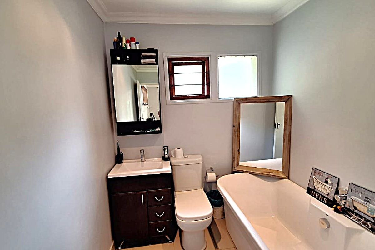 A functional bathroom featuring a vanity with integrated basin, a standard toilet, and a bathtub, finished with neutral wall tones.