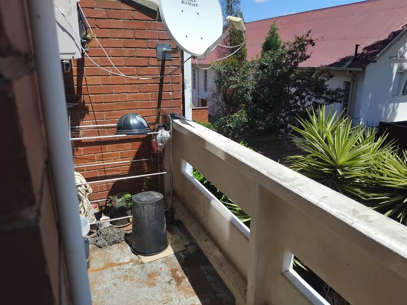 A functional balcony area featuring a brick wall, concrete balustrade, and an installed satellite dish, offering an outdoor space for the apartment.
