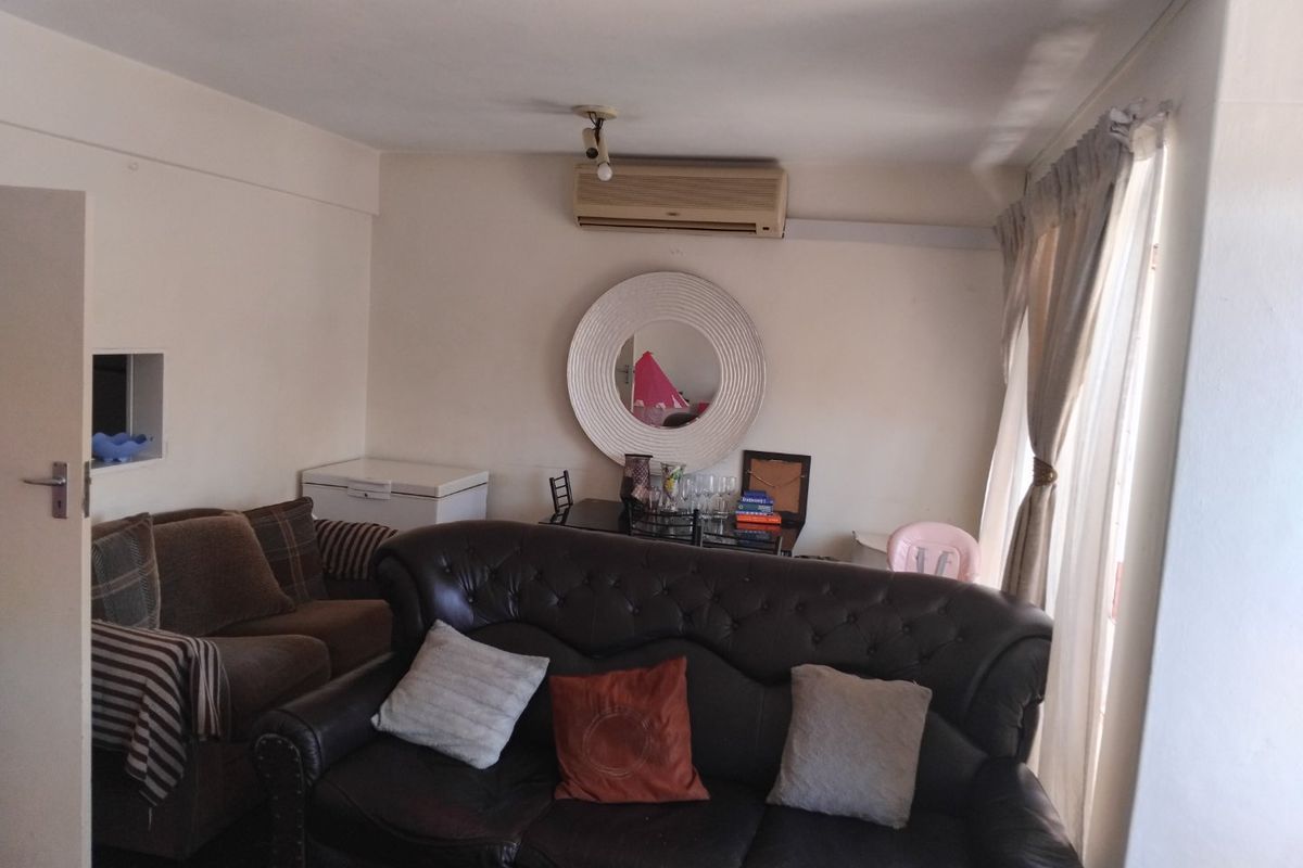 A living room area featuring a wall-mounted split-system air conditioner and window curtain tracks.