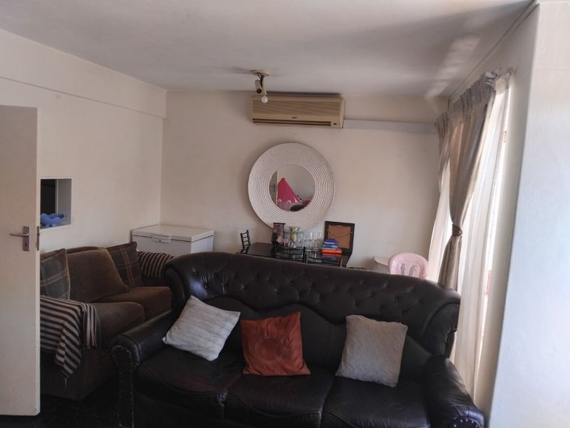 A living room area featuring a wall-mounted split-system air conditioner and window curtain tracks.
