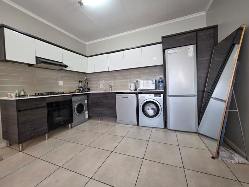 Modern kitchen featuring dark wood-grain and white cabinetry, tiled flooring, integrated appliances, and a neutral tiled backsplash.
