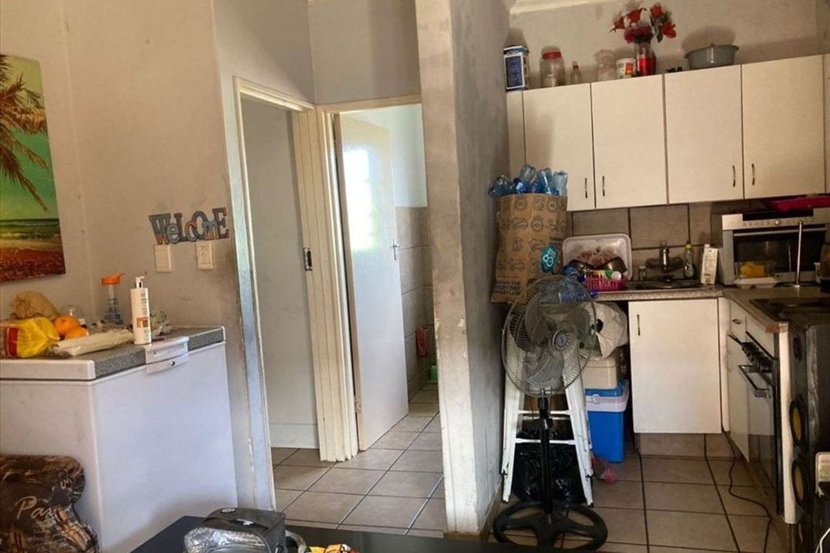Open plan kitchen area featuring built-in cabinetry and tiled flooring, requiring cosmetic updates to improve the overall aesthetic and condition of the space.