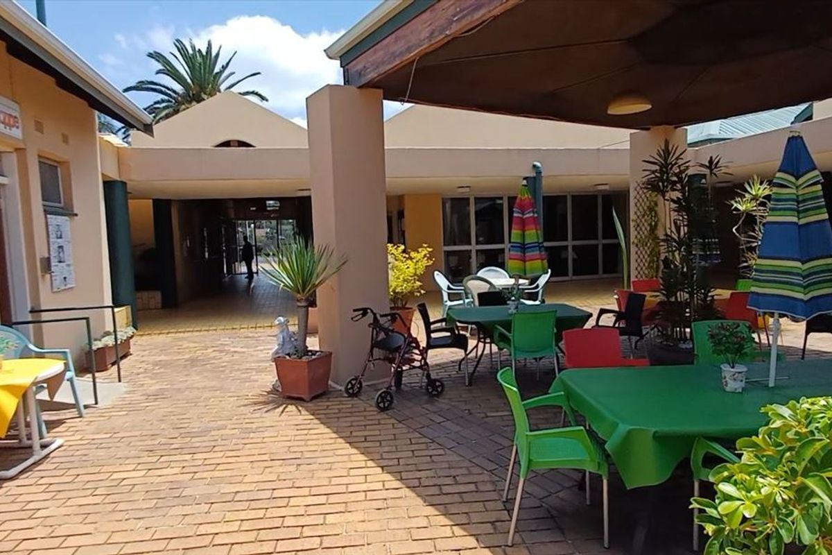 A spacious covered outdoor patio area featuring brick paving and direct access to the building interior, suitable for communal or residential use.
