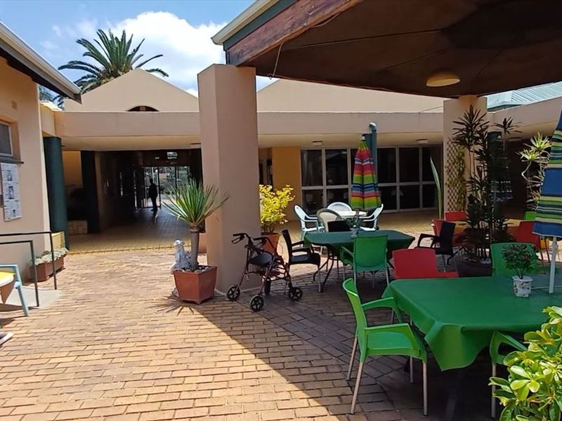 A spacious covered outdoor patio area featuring brick paving and direct access to the building interior, suitable for communal or residential use.