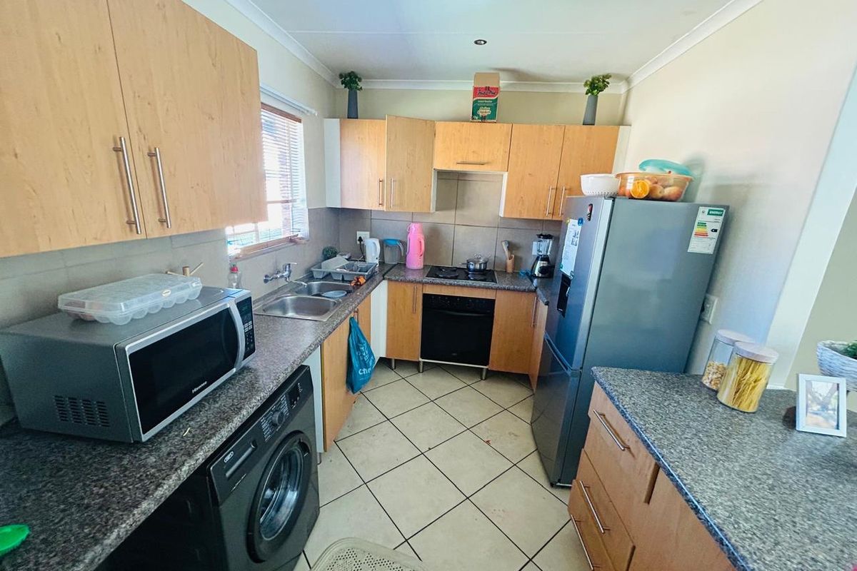 Functional kitchen featuring laminate cabinetry, granite countertops, built-in oven, hob, and tiled flooring, offering a practical layout for daily meal preparation.