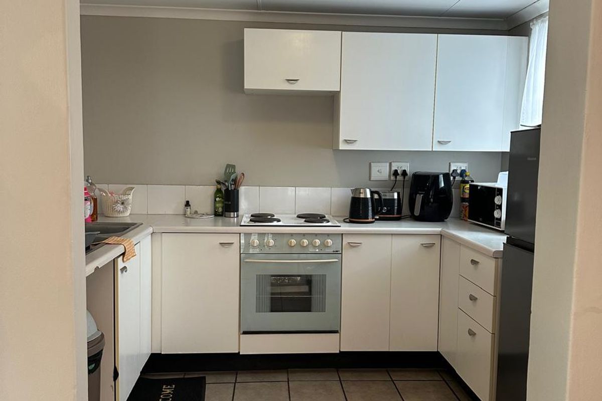 A functional kitchen featuring white cabinetry, tiled flooring, and a built-in electric stove and oven, offering a clean and practical workspace.