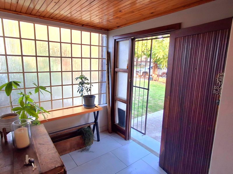 Entrance foyer featuring a timber ceiling, tiled flooring, and a large grid-pattern glass partition, providing a bright transition to the outdoor garden area.