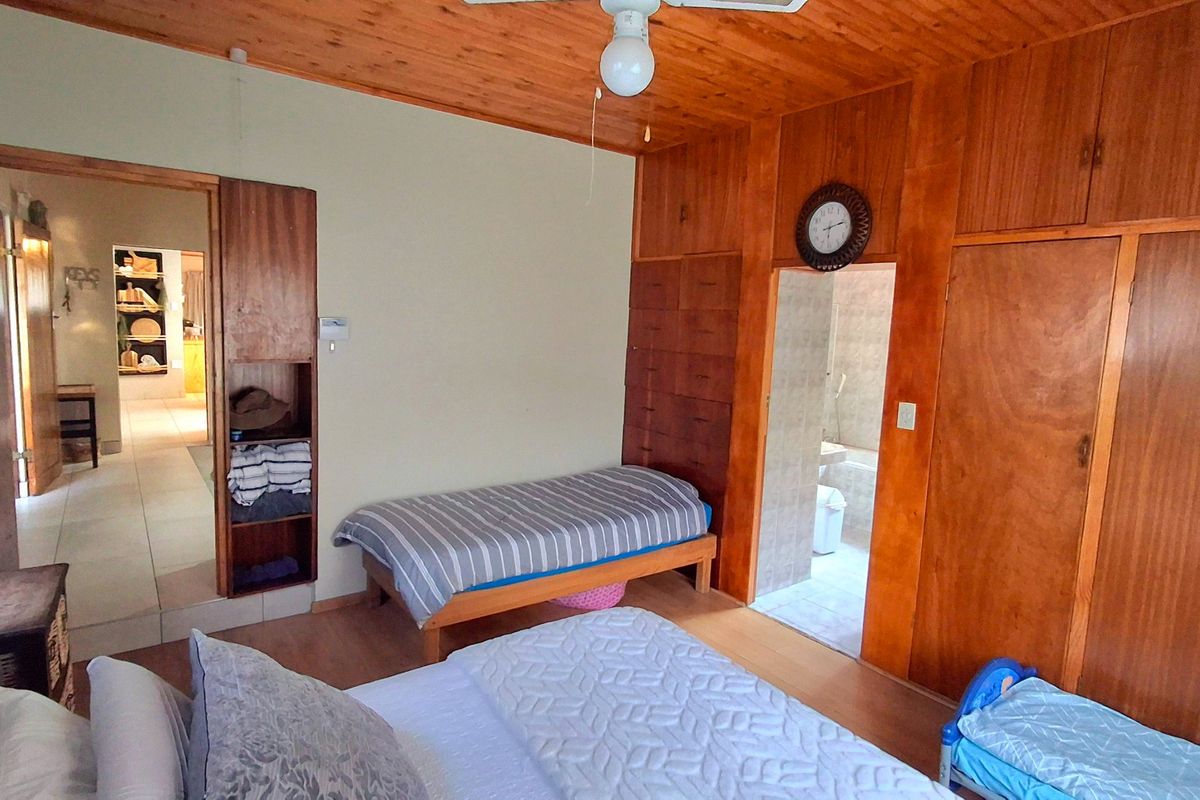 Bedroom featuring extensive built-in wooden cabinetry, a wooden ceiling with a fan, and direct access to an en-suite bathroom.