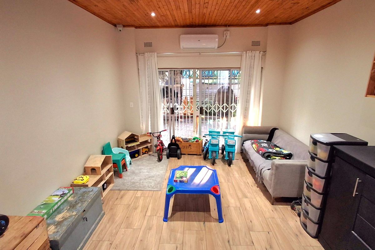 A living room featuring wood-look tile flooring, a timber-paneled ceiling with recessed lighting, and a sliding glass door providing access to the exterior.