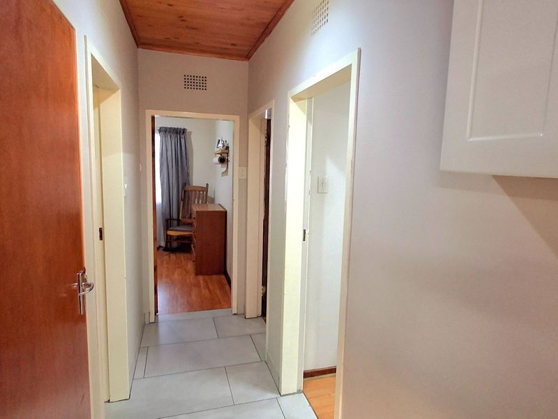 A functional hallway featuring tiled flooring and a timber-paneled ceiling, providing access to multiple rooms within the home.