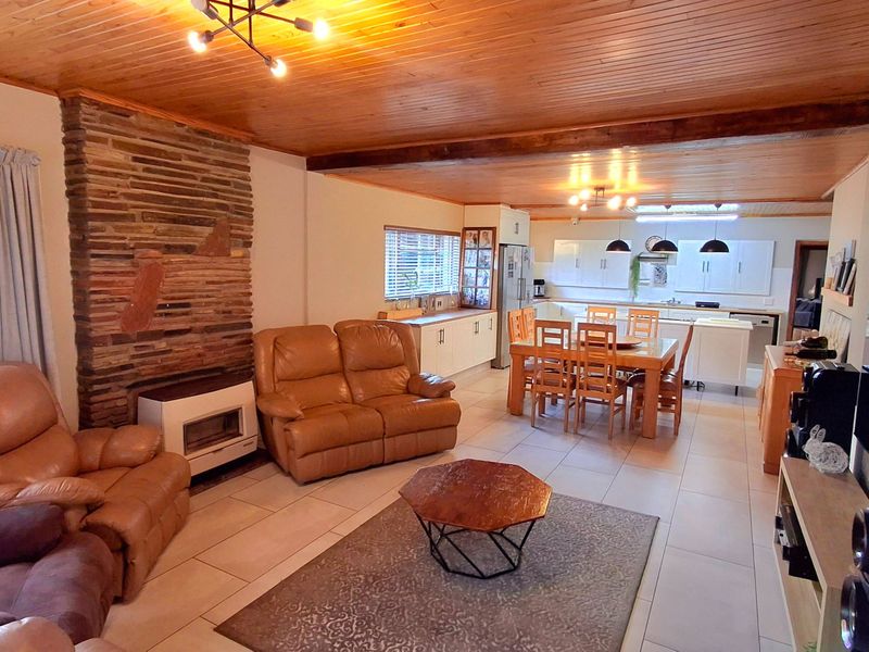 Spacious open-plan living and dining area featuring a stone fireplace, timber ceilings, and a functional kitchen with island seating.