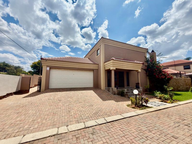 Front elevation of a townhouse featuring a paved driveway, double garage, and a covered entrance with stone cladding details.