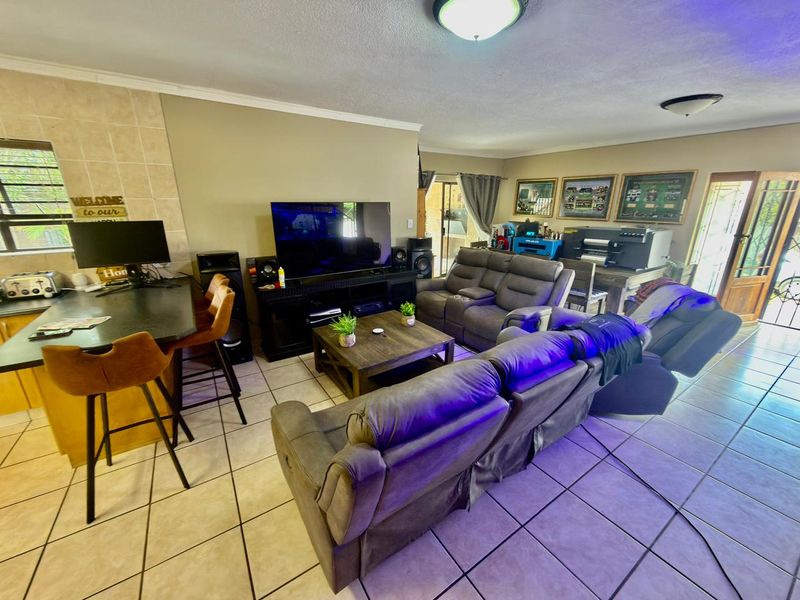 Open-plan living area featuring tiled flooring, a breakfast bar, and direct access to the outdoor space through a sliding glass door.
