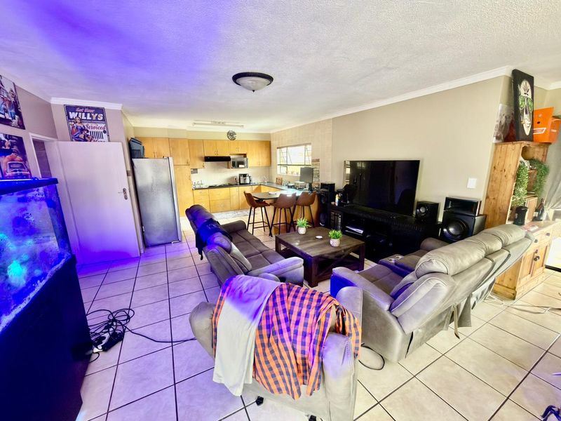 Open-plan living and kitchen area featuring tiled flooring, built-in cabinetry, and a breakfast bar, creating a functional combined space.
