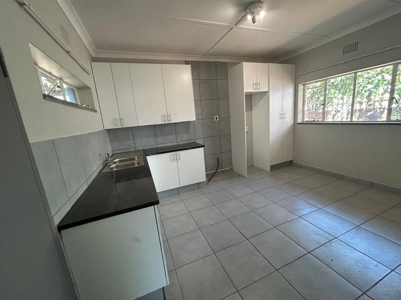 A clean, functional kitchen featuring white cabinetry, dark granite countertops, tiled flooring, and a tiled backsplash, offering a neutral canvas for personalization.