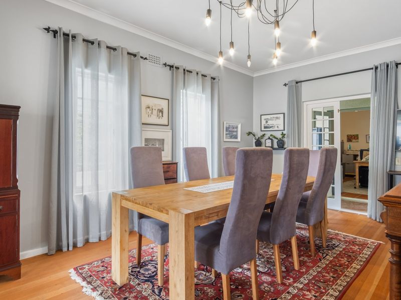 A well-maintained dining room featuring polished hardwood floors, elegant french doors, and contemporary pendant lighting, creating a bright and inviting atmosphere.