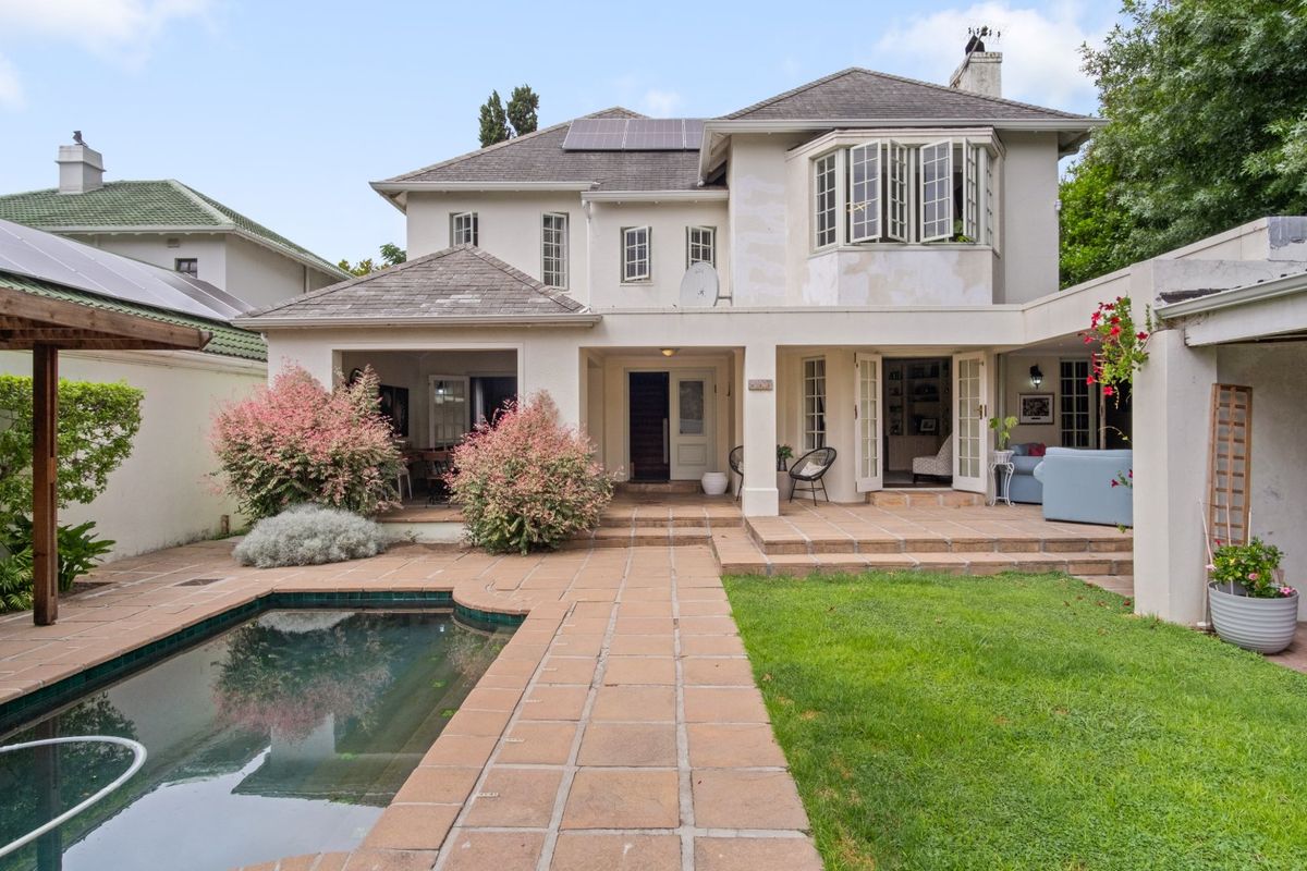 Rear view of the house featuring a tiled patio, swimming pool, and garden area with access through multiple sets of french doors.