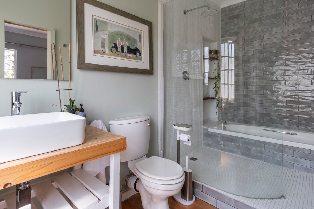 Modern bathroom featuring a vessel sink on a wooden vanity, a walk-in shower with glass screen, and stylish grey subway tiling.