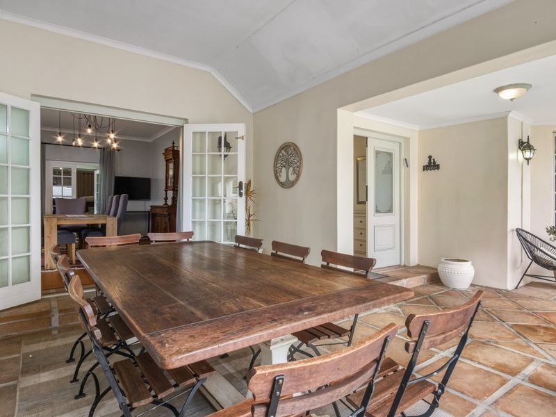 A spacious covered patio featuring terracotta tile flooring, a vaulted ceiling, and direct access to the interior living areas through classic french doors.