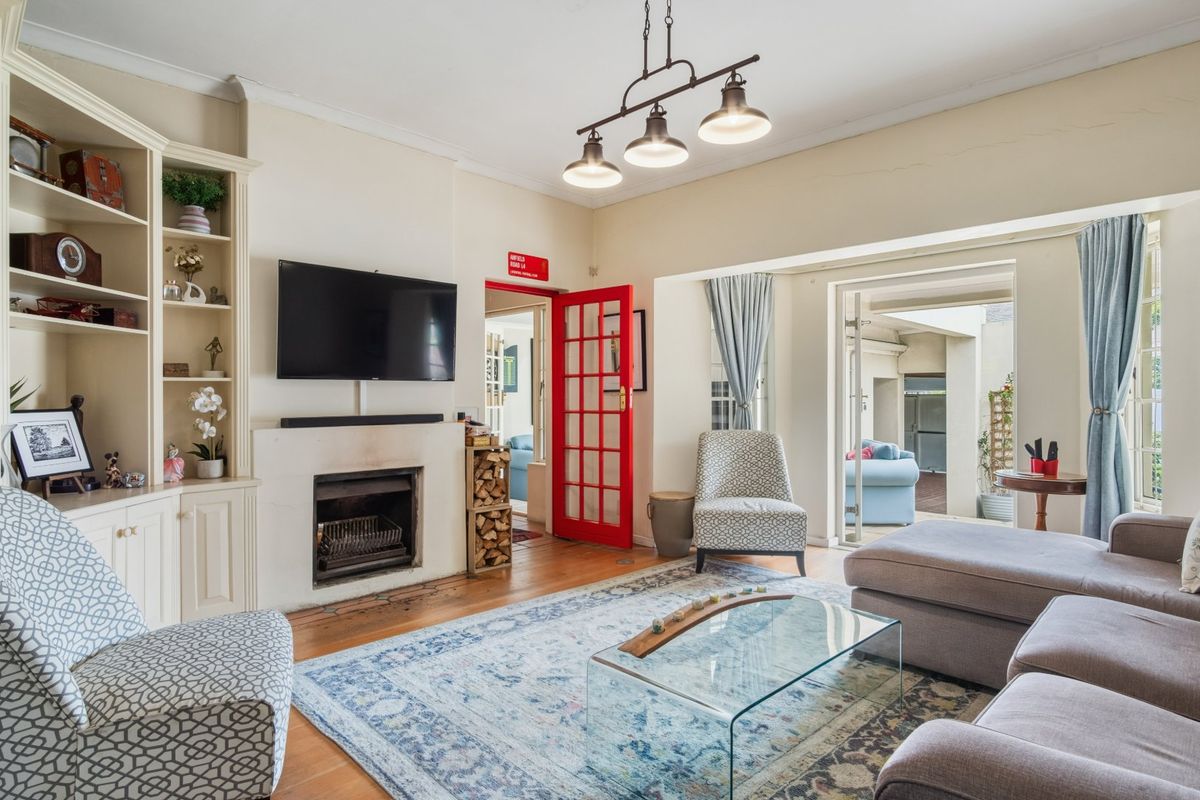 A cozy living room featuring built-in shelving, a fireplace, and hardwood floors, with direct access to an outdoor patio area through french doors.