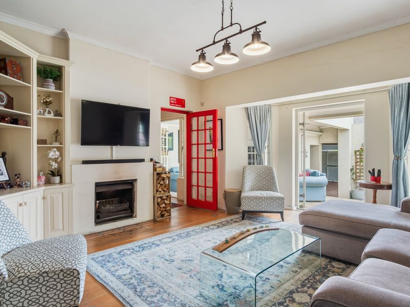 A cozy living room featuring built-in shelving, a fireplace, and hardwood floors, with direct access to an outdoor patio area through french doors.