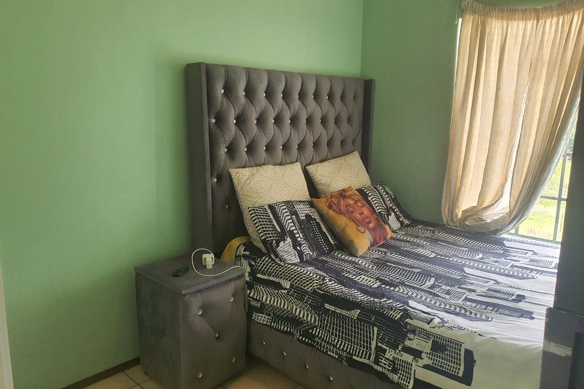 A bedroom featuring tiled flooring and a window with a curtain rail, providing a functional space for rest.