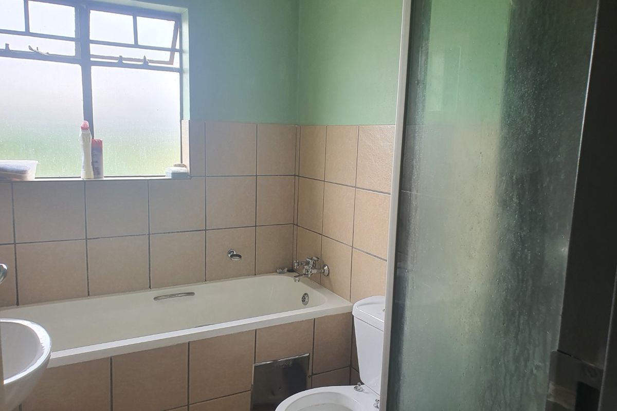 A functional bathroom featuring a bathtub, separate shower enclosure, toilet, and washbasin with neutral wall tiling.