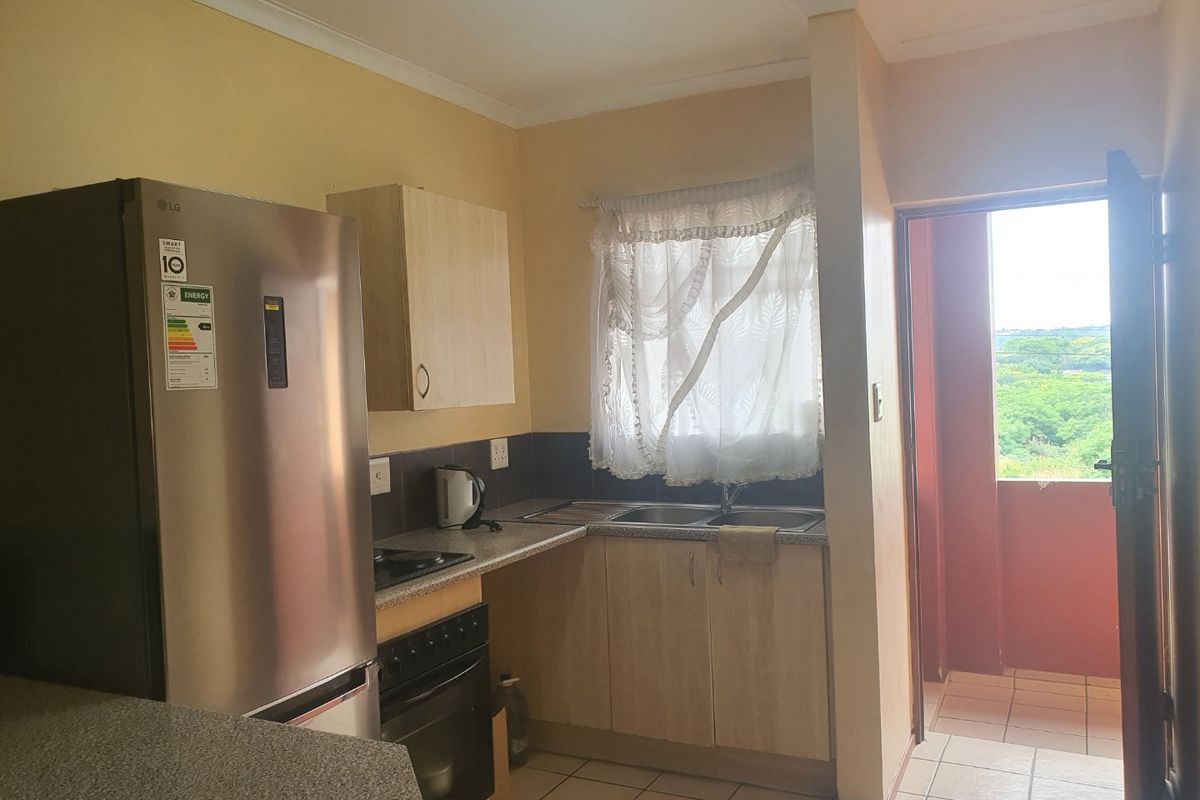 A functional kitchen featuring built-in cabinetry, laminate countertops, a stainless steel sink, and an integrated oven, with direct access to an outdoor balcony area.
