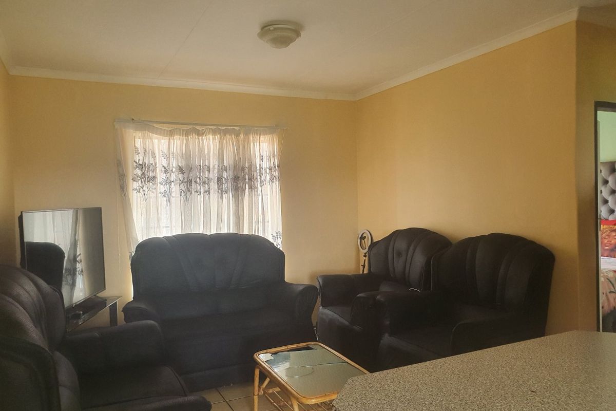 A functional living room area featuring tiled flooring and neutral wall tones, providing a comfortable space for relaxation.