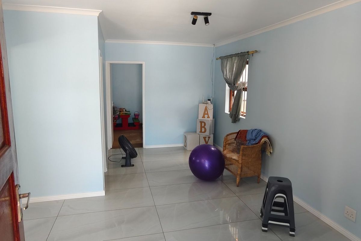 A bright, open living room featuring neutral light blue walls, large format floor tiles, and a clean, minimalist layout ready for personalization.