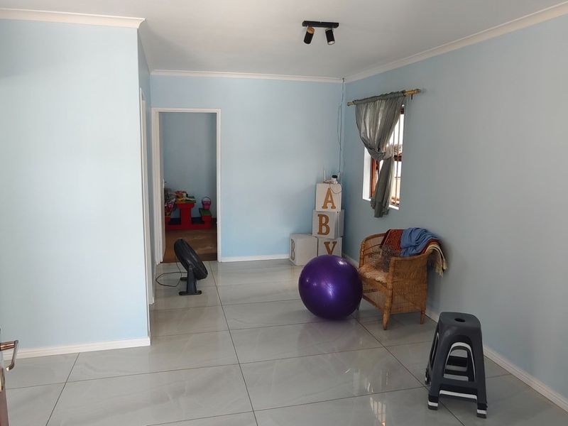 A bright, open living room featuring neutral light blue walls, large format floor tiles, and a clean, minimalist layout ready for personalization.