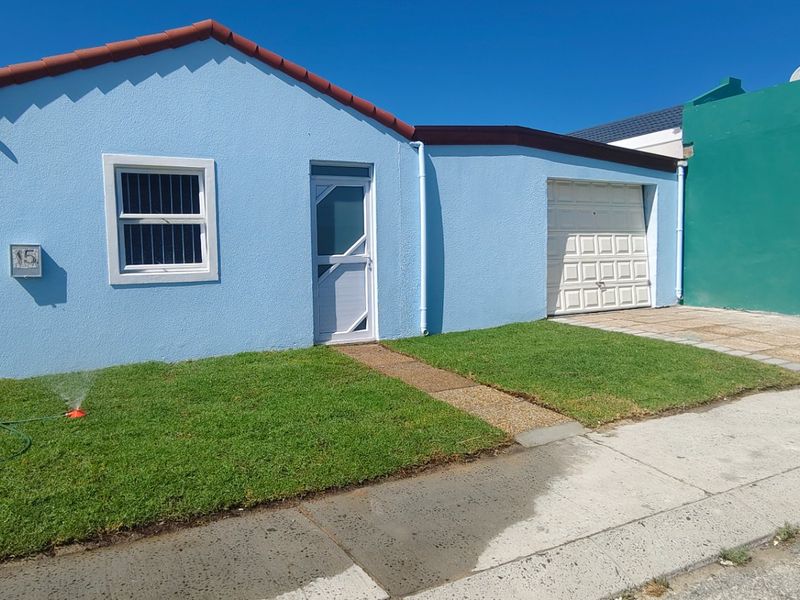 Front elevation of a single-story house featuring a tiled roof, single garage, security gate, and a small front lawn.