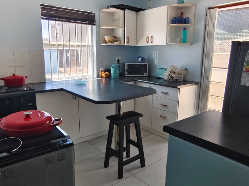 Compact kitchen featuring built-in cabinetry, laminate countertops, tiled splashback, and integrated oven with hob, offering a functional layout with natural light.