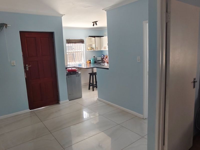 Open plan living area featuring tiled flooring, connecting to a functional kitchen space with built-in cabinetry and counter space.
