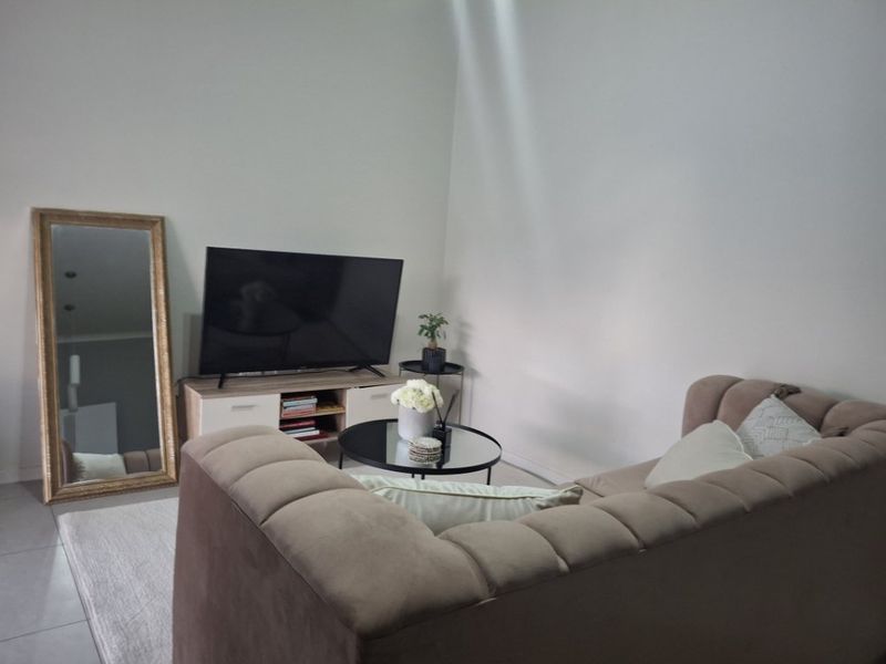 A comfortable living room area featuring neutral wall tones and tiled flooring, providing a versatile space for relaxation and entertainment.