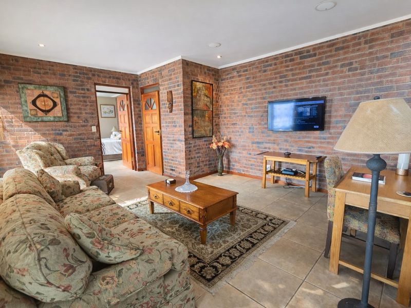 A living room featuring exposed brick walls, tiled flooring, and recessed downlighting, providing a rustic and textured aesthetic.