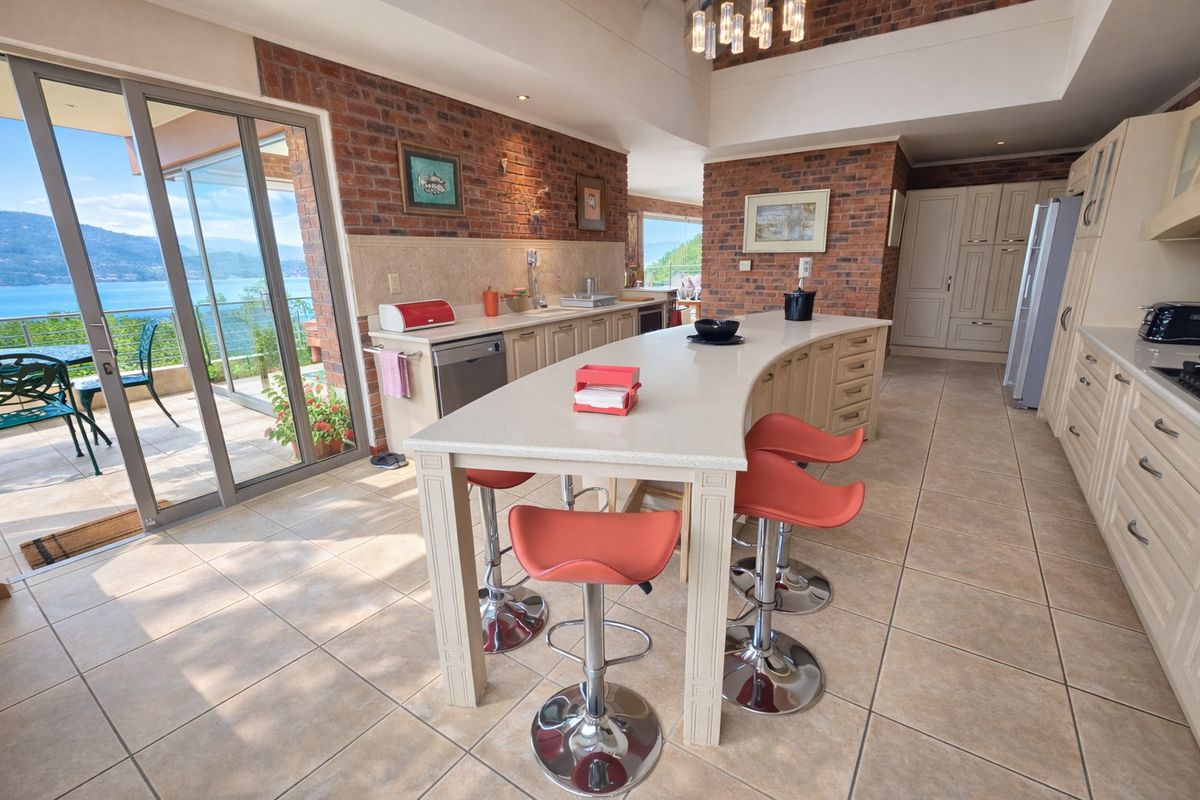 Spacious kitchen featuring a large central island, exposed brick accents, and direct access to a balcony with scenic water views.