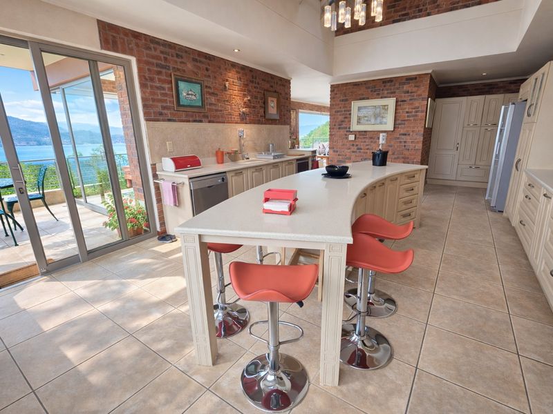 Spacious kitchen featuring a large central island, exposed brick accents, and direct access to a balcony with scenic water views.
