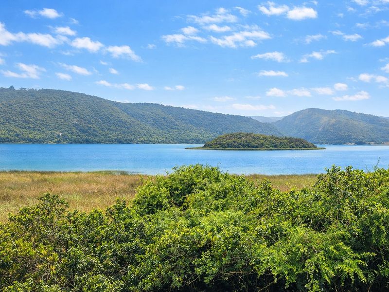 A scenic view of a tranquil lake surrounded by lush green hills and a small island.