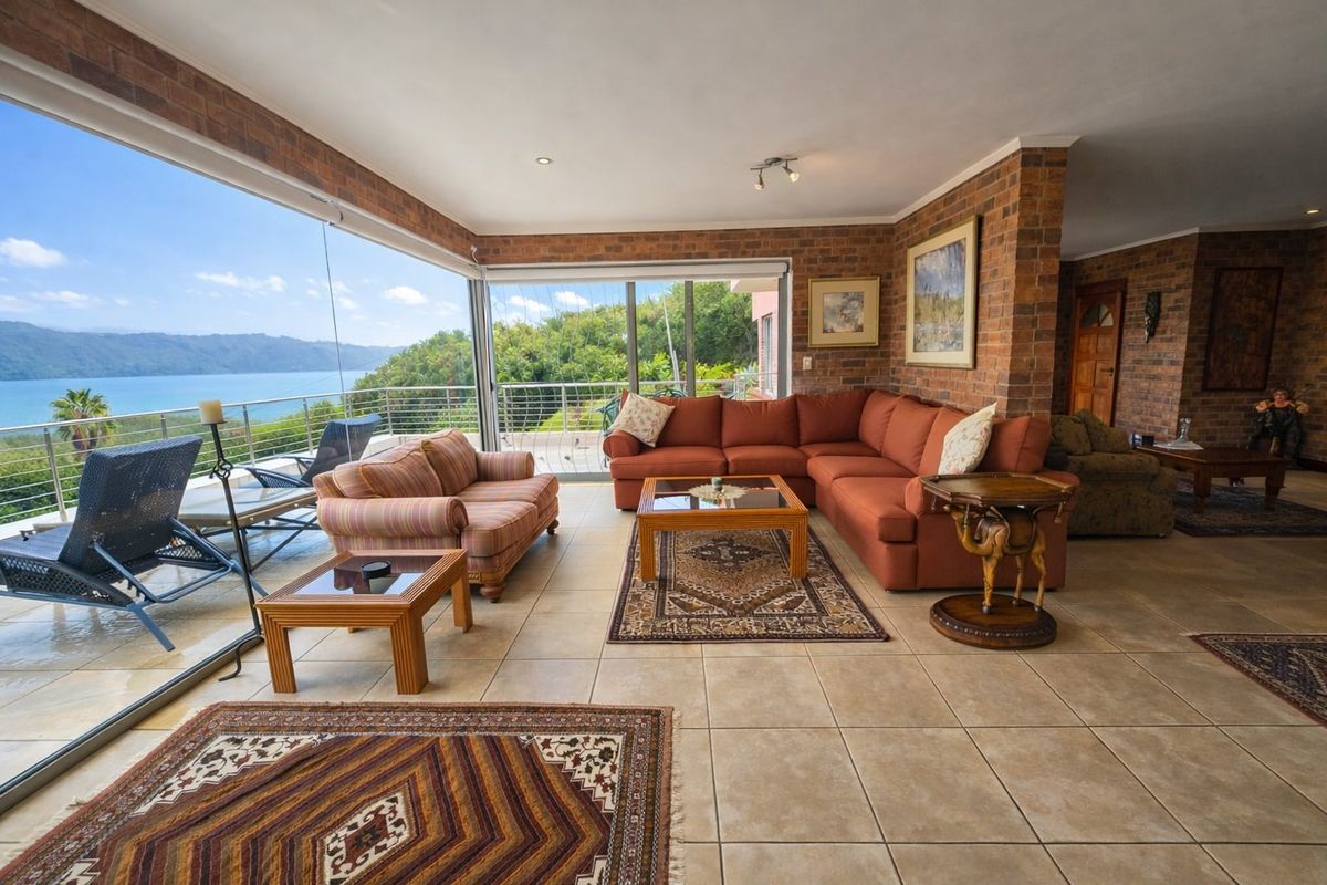 Spacious living area featuring exposed brick walls, tiled flooring, and large sliding glass doors that open to a scenic waterfront view.