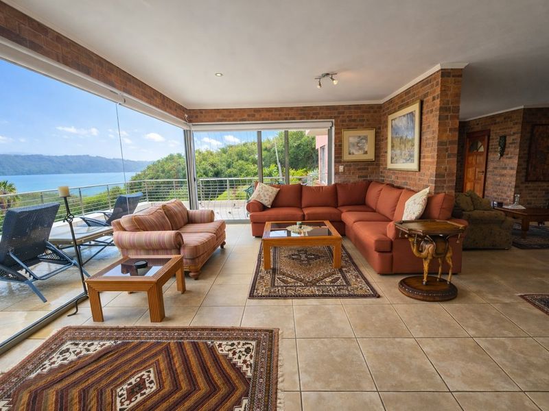 Spacious living area featuring exposed brick walls, tiled flooring, and large sliding glass doors that open to a scenic waterfront view.