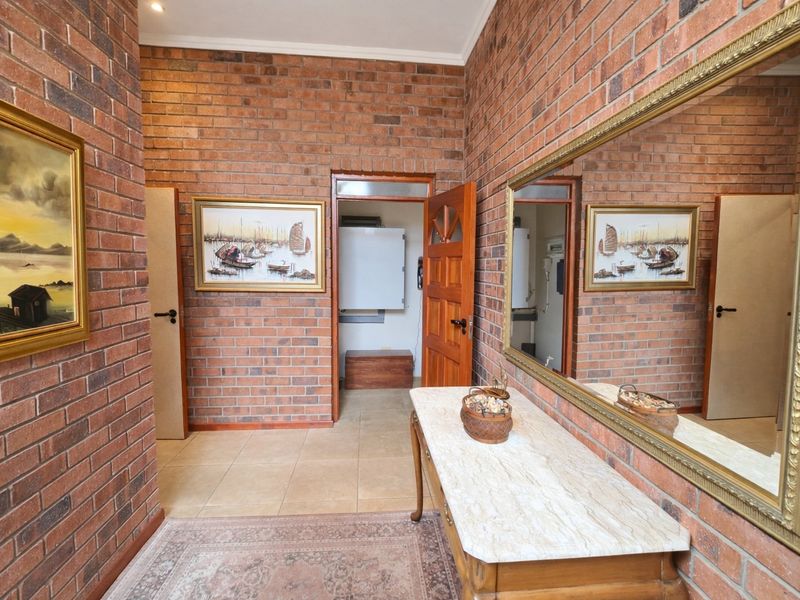 A spacious hallway featuring exposed brick walls, tiled flooring, and solid timber doors, providing a warm and textured entrance to the home.