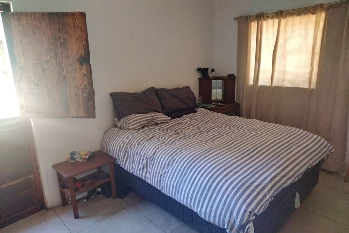A bedroom featuring tiled flooring and a rustic wooden shutter, requiring cosmetic updates to improve the overall finish and appeal.