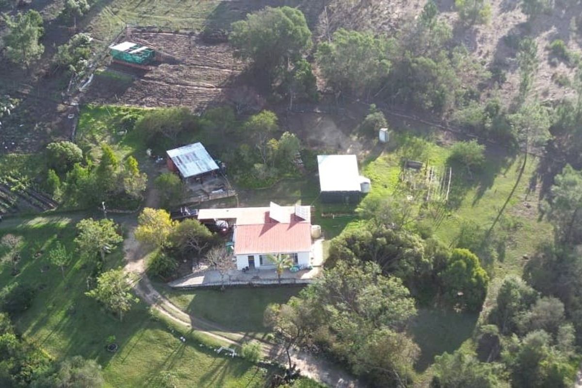 Aerial view of a rural farm property featuring a main residence, multiple outbuildings, solar panels, and surrounding landscaped grounds.