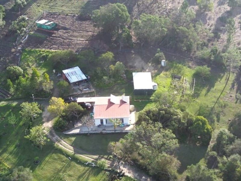 Aerial view of a rural farm property featuring a main residence, multiple outbuildings, solar panels, and surrounding landscaped grounds.