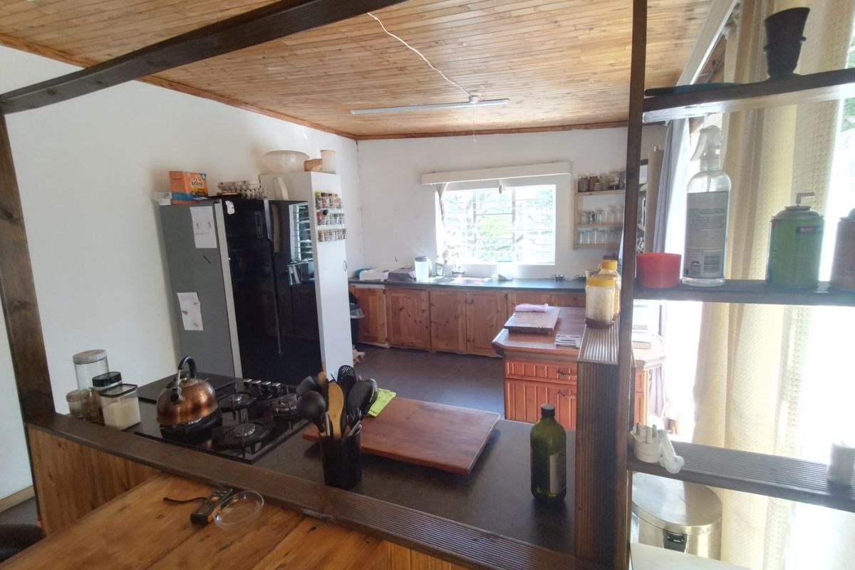 A functional kitchen featuring wooden cabinetry, a gas hob, and a timber-paneled ceiling, offering a rustic aesthetic with potential for modern updates.